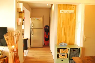 a kitchen with a refrigerator and a guitar in the doorway at Gruissan Terrasse jardin cosy et au calme in Gruissan