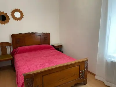 a bedroom with a wooden bed with a red bedspread at Maison gorges de la Pierre lys in Belvianes-et-Cavirac