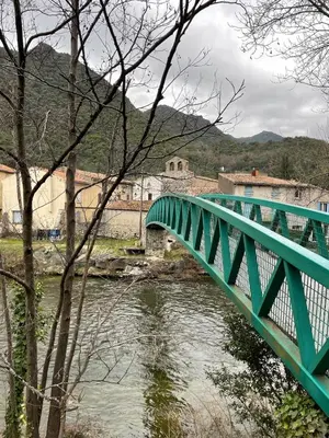a green bridge over a river in a town at Maison gorges de la Pierre lys in Belvianes-et-Cavirac