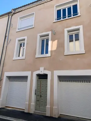 a building with two garage doors and a green door at Studio Gili Meno in Narbonne