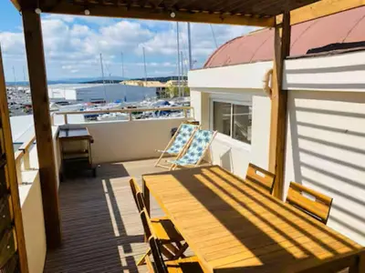 a balcony with a table and chairs on a boat at T3 with large roof-top terrace, harbor view in Gruissan
