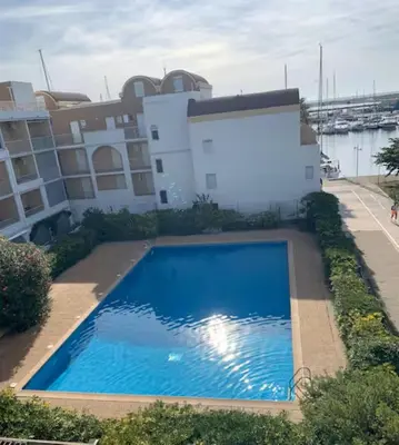 a large blue swimming pool in front of a building at T3 with large roof-top terrace, harbor view in Gruissan