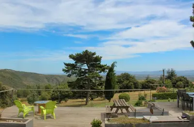 a patio with green chairs and a table and a view at Au Cammazou in Villanière