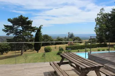 a wooden bench sitting on a deck next to a pool at Au Cammazou in Villanière