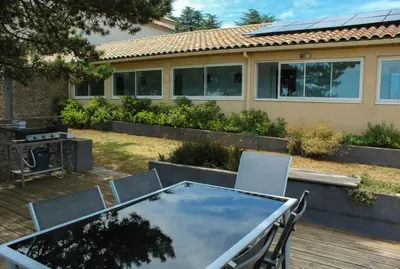 a table and chairs on a deck in front of a house at Au Cammazou in Villanière