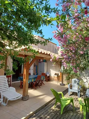 a patio with chairs and a table and a tree at Villa à Gruissan Mateille avec petit jardin et terrasse couverte in Gruissan