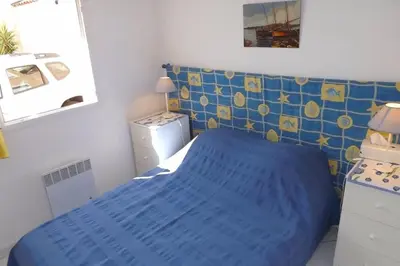 a small bedroom with a blue bed in it at Villa à Gruissan Mateille avec petit jardin et terrasse couverte in Gruissan