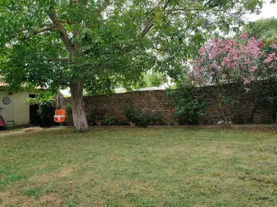 a tree in a yard next to a brick wall at La maison gourmande in Alzonne