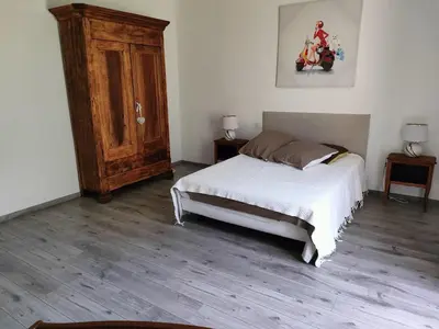 a bedroom with a bed and a wooden floor at La maison gourmande in Alzonne