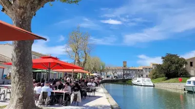 a group of people sitting at tables by a river at Maison accueillante à Trèbes avec 2 chambres in Trèbes