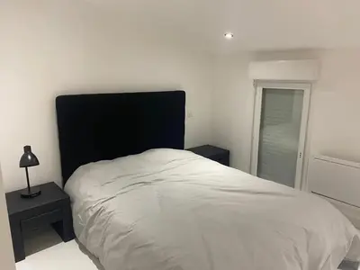 a white bed with a black headboard in a bedroom at Maison accueillante à Trèbes avec 2 chambres in Trèbes