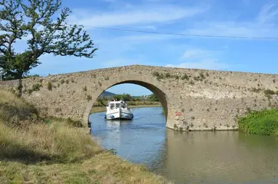 a boat in a river under a bridge at Maison accueillante à Trèbes avec 2 chambres in Trèbes