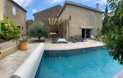 a swimming pool in front of a house at Relais des Vignerons, Chambres d'hôtes in Conilhac-Corbières