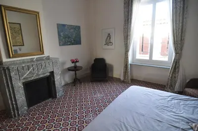 a bedroom with a fireplace and a bed and a chair at Relais des Vignerons, Chambres d'hôtes in Conilhac-Corbières