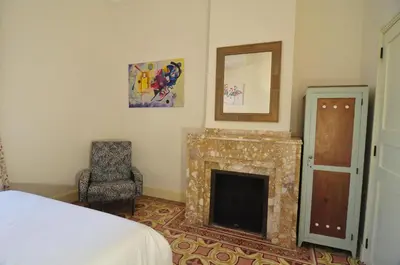 a bedroom with a fireplace and a chair and a mirror at Relais des Vignerons, Chambres d'hôtes in Conilhac-Corbières