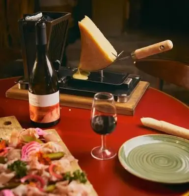 a table with a bottle of wine and a pizza and a glass at chambre et table d'hôte au coin de la cité in Carcassonne