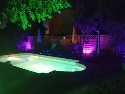 a swimming pool at night with purple lights at chambre et table d'hôte au coin de la cité in Carcassonne