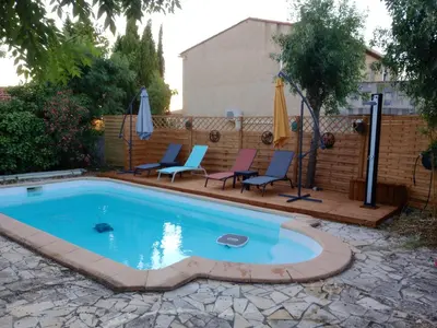 a swimming pool with two chairs and an umbrella at chambre et table d'hôte au coin de la cité in Carcassonne