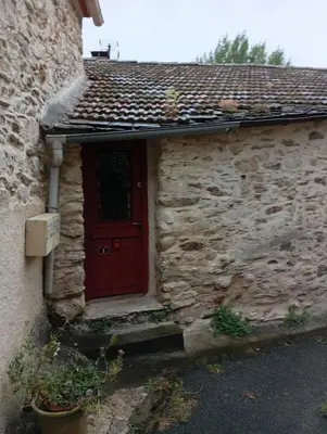 a red door on the side of a stone building at Appartement prémian in Prémian