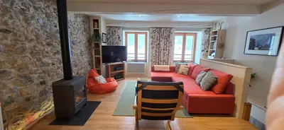 a living room with a red couch and a fireplace at Les Quatre Saisons in Montaillou