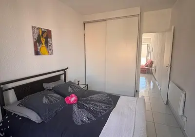 a bedroom with a bed with a pink flower on it at Charmant T2 à 1 min de la plage in Port-la-Nouvelle