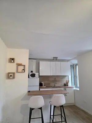 a kitchen with two white stools and a kitchen counter at Studio hypercentre in Castelnaudary