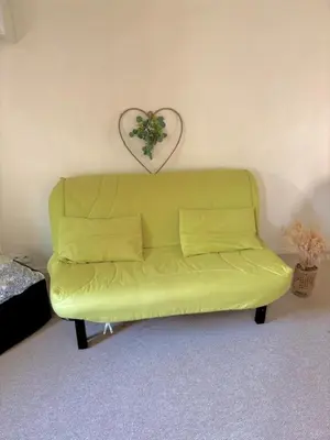 a yellow couch in a room with a heart on the wall at Studio équipé in Narbonne