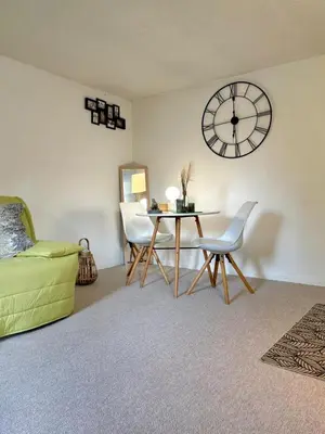 a living room with a table and a clock on the wall at Studio équipé in Narbonne