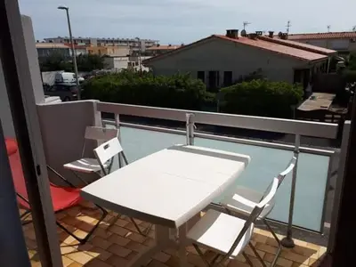 a white table and chairs on a balcony at Bel appartement proche de la mer in Port-la-Nouvelle