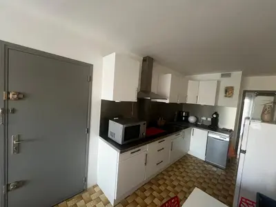 a kitchen with white cabinets and a microwave at Bel appartement proche de la mer in Port-la-Nouvelle
