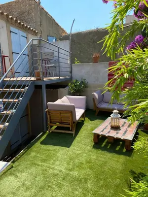 a small yard with a patio with chairs and a table at Maison bougainvillier Gruissan Village in Gruissan