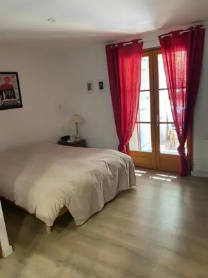 a bedroom with a bed with red curtains and a window at Maison bougainvillier Gruissan Village in Gruissan