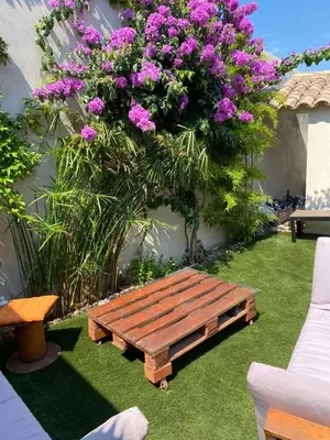 a wooden bench sitting on the grass with flowers at Maison bougainvillier Gruissan Village in Gruissan