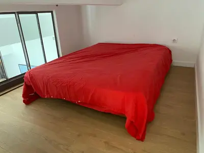 a red bed in a room with windows at Maison bougainvillier Gruissan Village in Gruissan