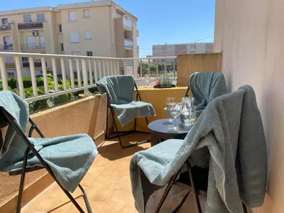 a balcony with chairs and a table with glasses on it at La Pause Nouvelle - CLIM - 5 min de la plage in Port-la-Nouvelle