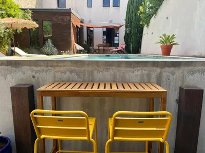 a table and two yellow chairs next to a pool at Chambre À la croisée des sens in Carcassonne