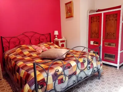 a bedroom with a bed with a red wall at Chambre d hôtes Cap instant in Capestang
