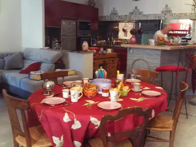 a table with a red table cloth on it in a kitchen at Chambre d hôtes Cap instant in Capestang