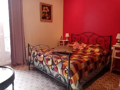a bedroom with a bed with a red wall at Chambre d hôtes Cap instant in Capestang