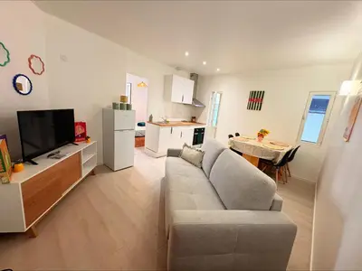 a living room with a couch and a tv and a kitchen at Lylo in Carcassonne