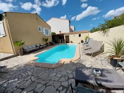 a swimming pool in a patio with a table and chairs at Maison calme avec piscine in Montredon