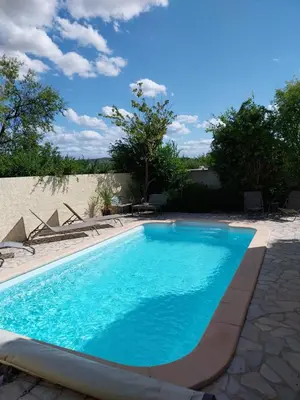 a swimming pool with blue water in a yard at Maison calme avec piscine in Montredon