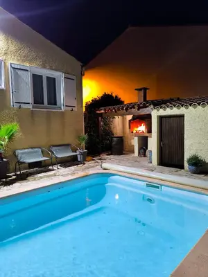 a swimming pool in front of a house with a fireplace at Maison calme avec piscine in Montredon
