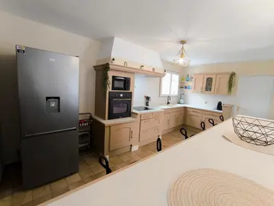 a large kitchen with a refrigerator and a sink at Maison calme avec piscine in Montredon