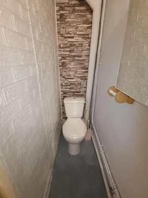 a bathroom with a white toilet in a brick wall at Maison entière Les Maisons de Gaia in Tuchan