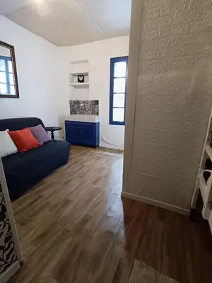 a living room with a blue couch and wooden floors at Maison entière Les Maisons de Gaia in Tuchan