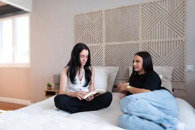 two women sitting on a bed reading a book at Villa à Castres, Maison 10 personnes avec piscine privée, jardin et 5 chambres in Castres