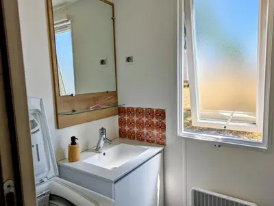 a small bathroom with a sink and a window at Mobil home 6 à 8 personnes climatisé in Saint-Papoul