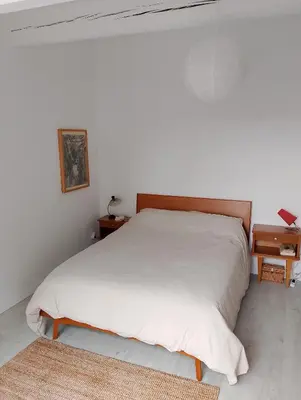 a bedroom with a white bed with a wooden headboard at Jolie maison vintage, à 15mn de Lagrasse in Taurize