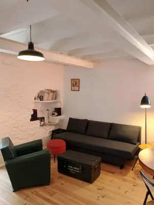 a living room with a black couch and a red stool at Jolie maison vintage, à 15mn de Lagrasse in Taurize
